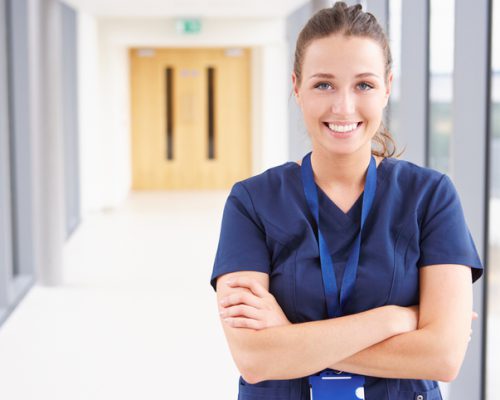 Portrait Of Female Nurse Standing In Hospital Corridor