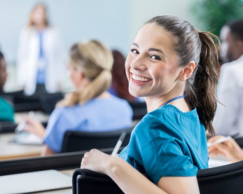 Beautiful young Hispanic female medical student smiles over her shoulder while attending class.